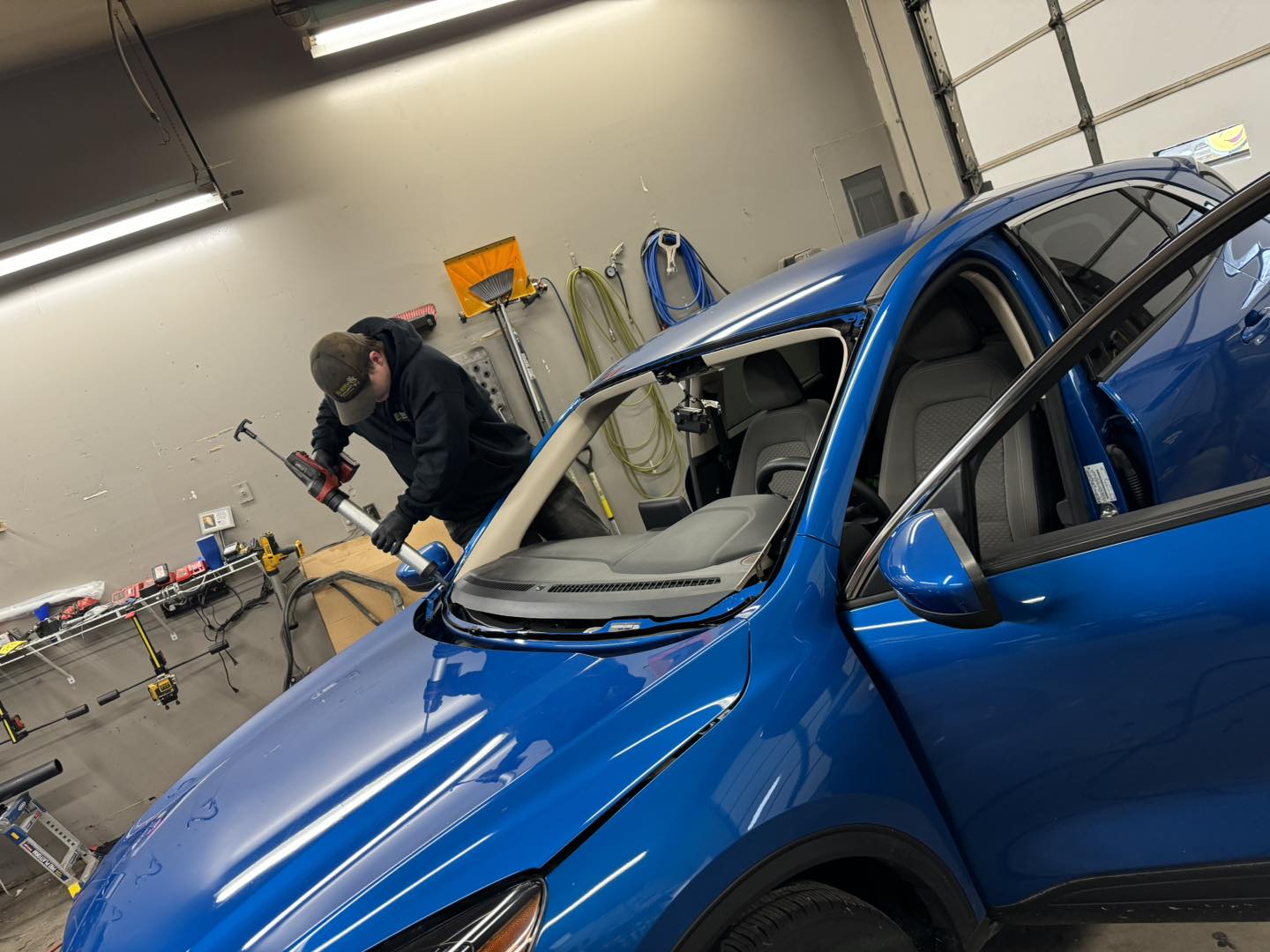 B-Rite technician applying urethane during a windshield replacement on a blue SUV